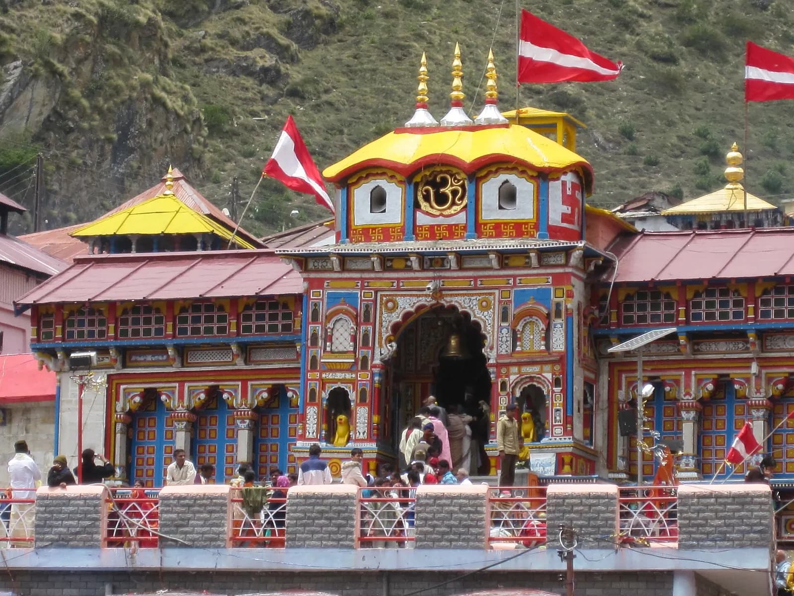 Brightly painted Badrinath temple on the Alaknanda with snow peaks behind