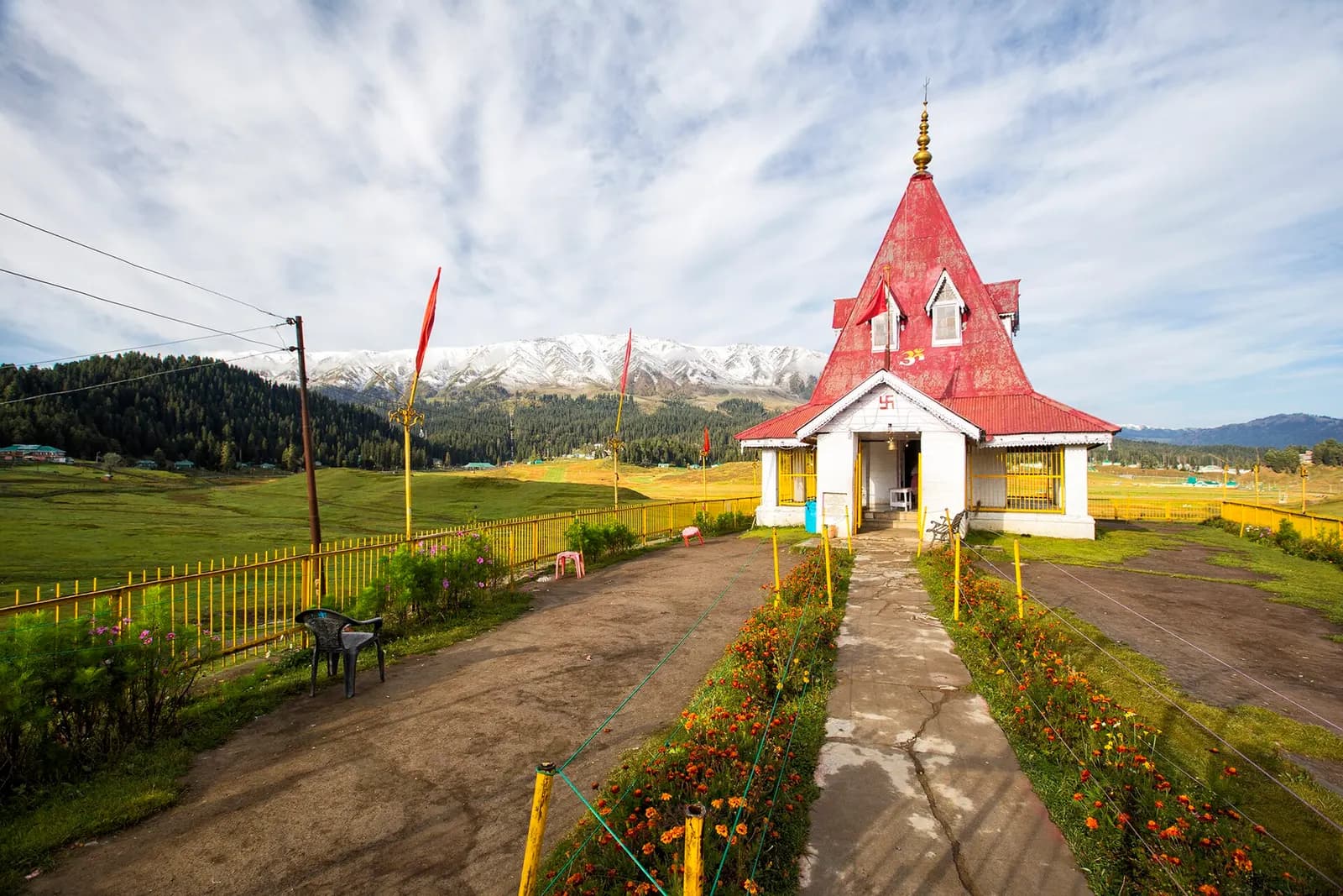 Snow-covered meadow and gondola cables at Gulmarg with pine forest and the Pir Panjal range