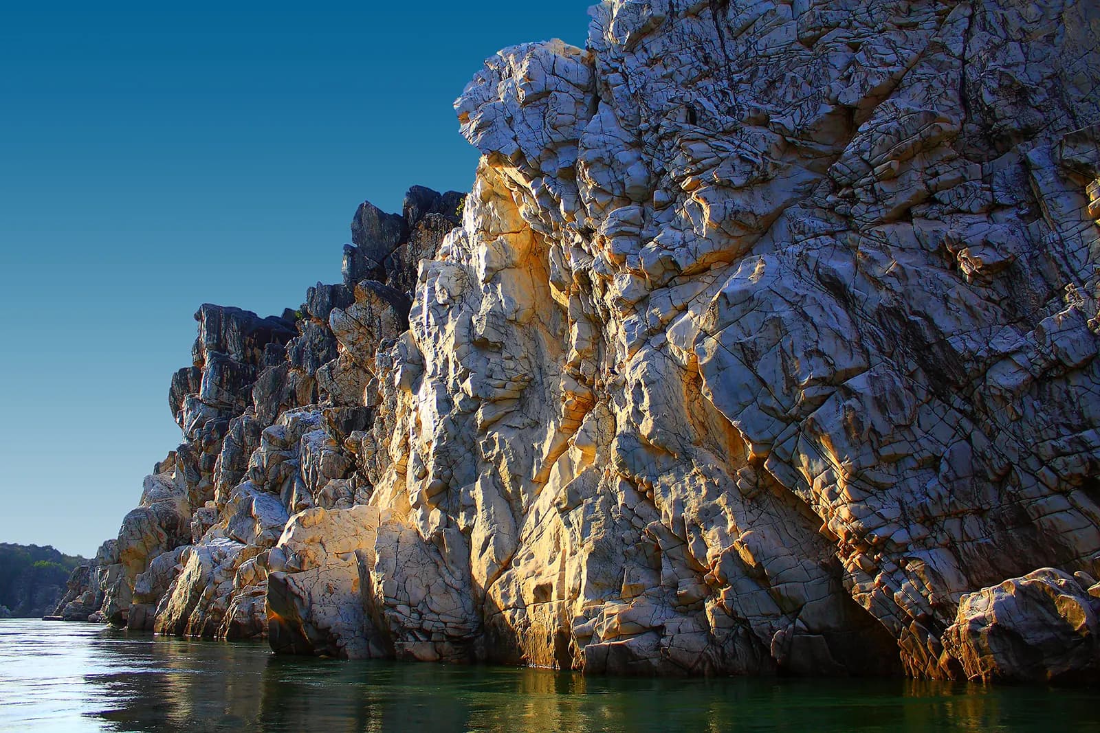 Boats on the green Narmada between the white Marble Rocks cliffs at Bhedaghat
