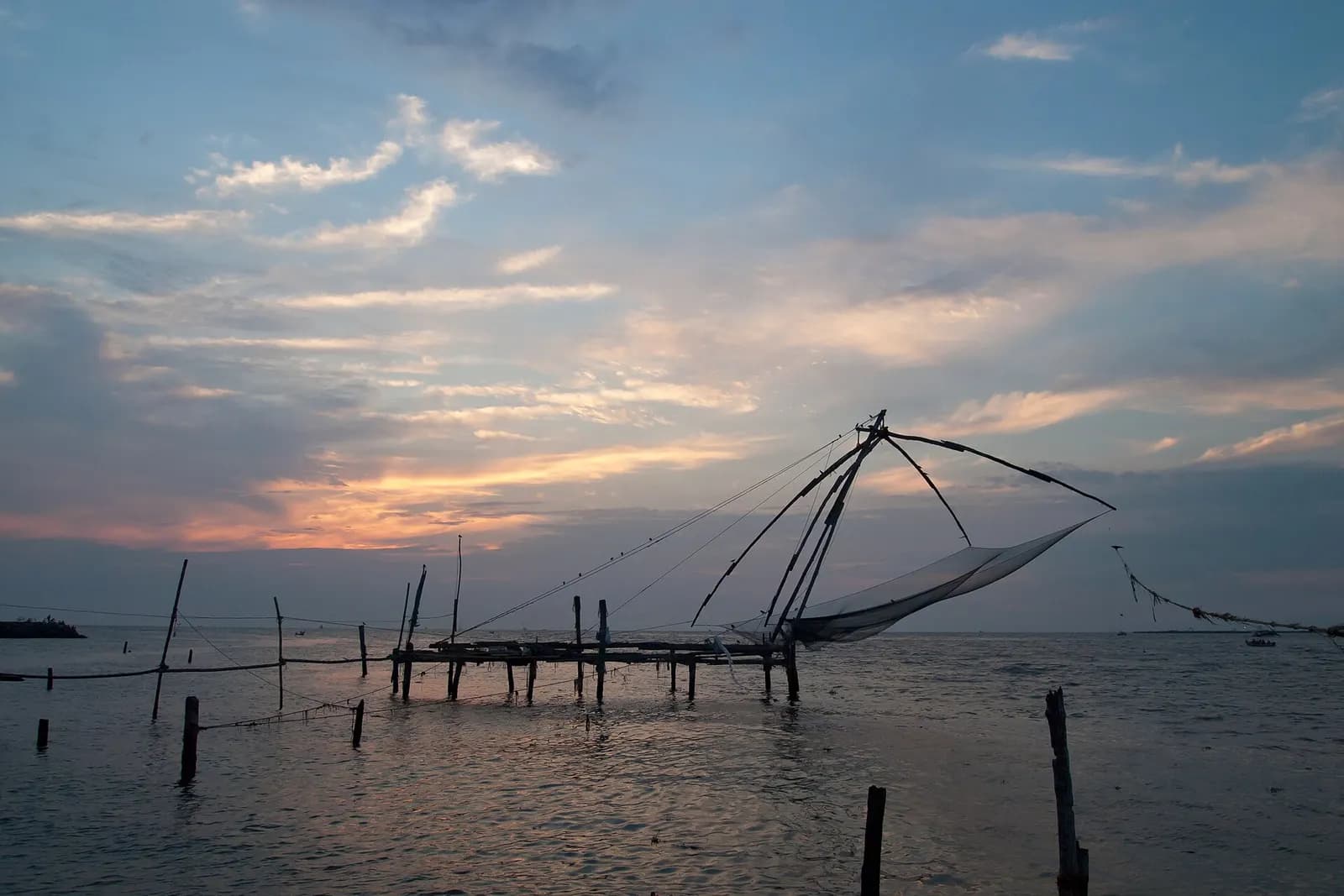 Cantilevered Chinese fishing nets on the Fort Kochi waterfront at dusk