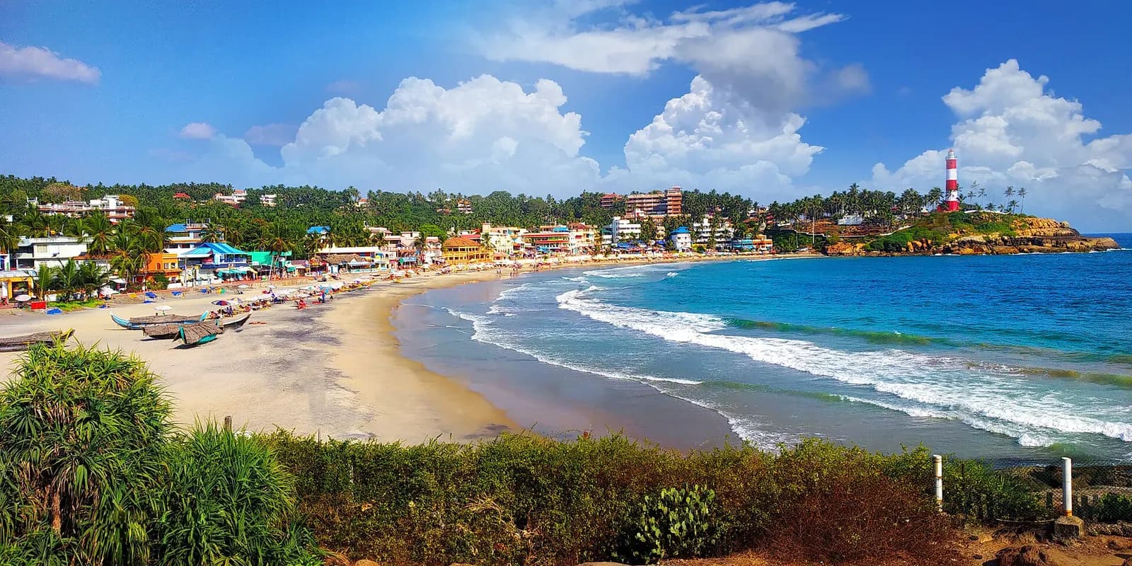 The striped lighthouse above the crescent bay at Kovalam beach in Kerala