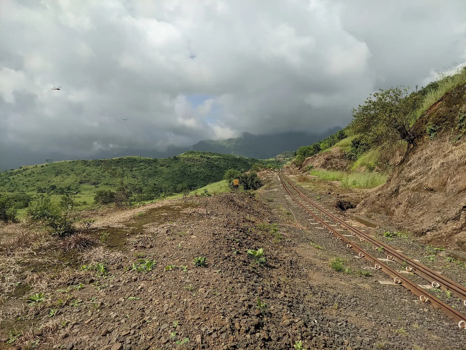 A red laterite forest path and viewpoint on the plateau edge at Matheran