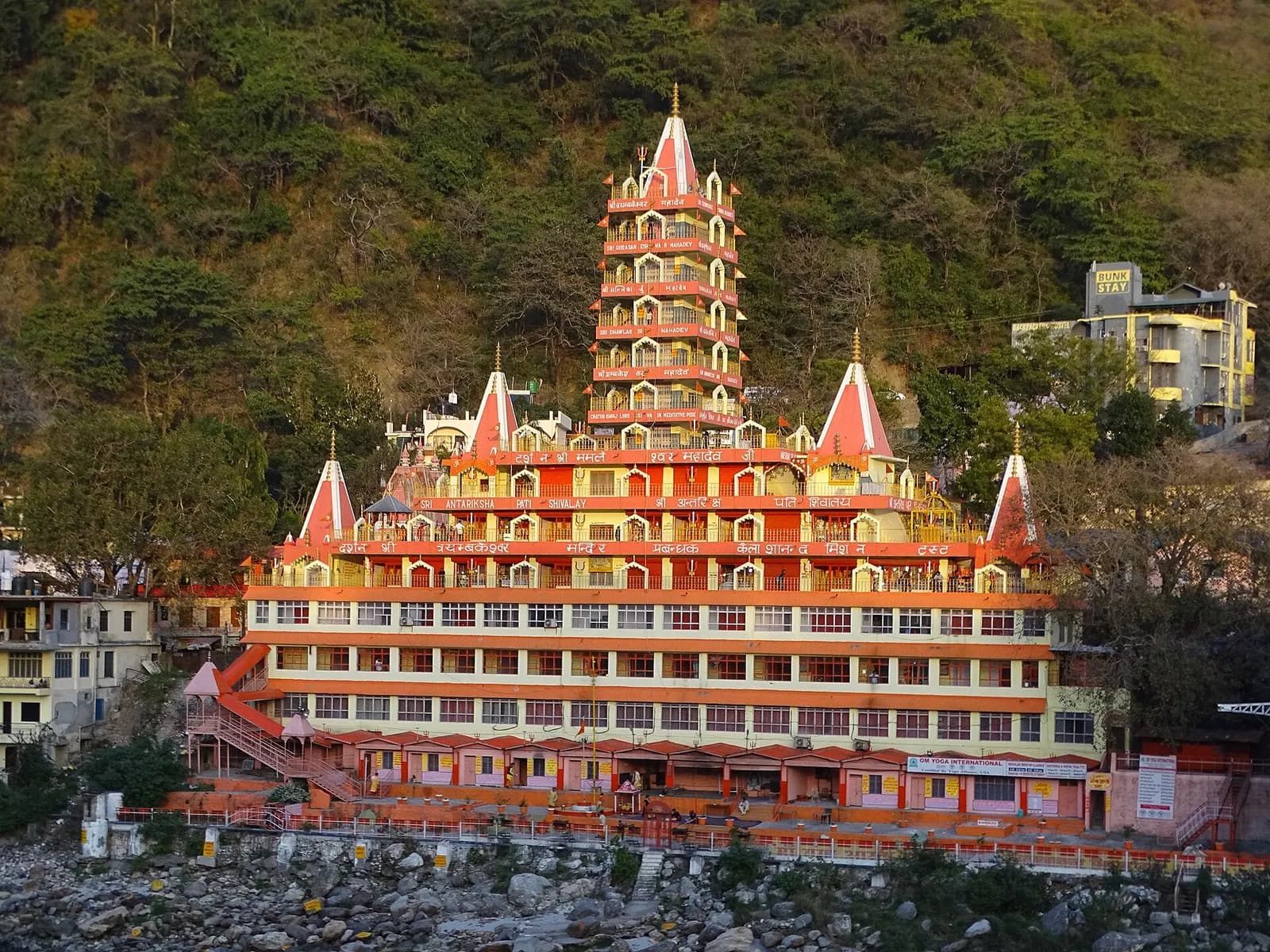 Suspension bridge over the green Ganga at Rishikesh with temples and forested hills