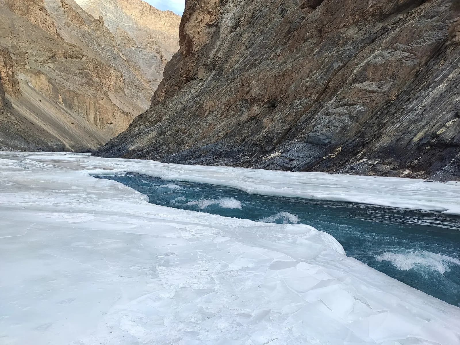 Trekkers walking the frozen Zanskar river between canyon walls on the Chadar trek in Ladakh