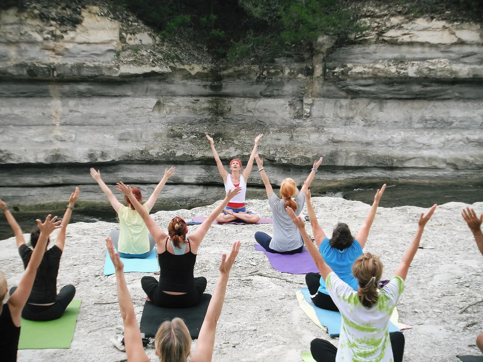 A group holding a seated yoga posture on mats at sunrise during an outdoor class
