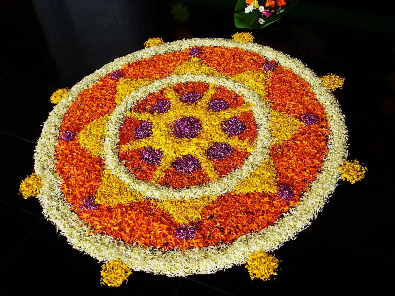 A circular pookkalam of flower petals laid on a Kerala courtyard for Onam